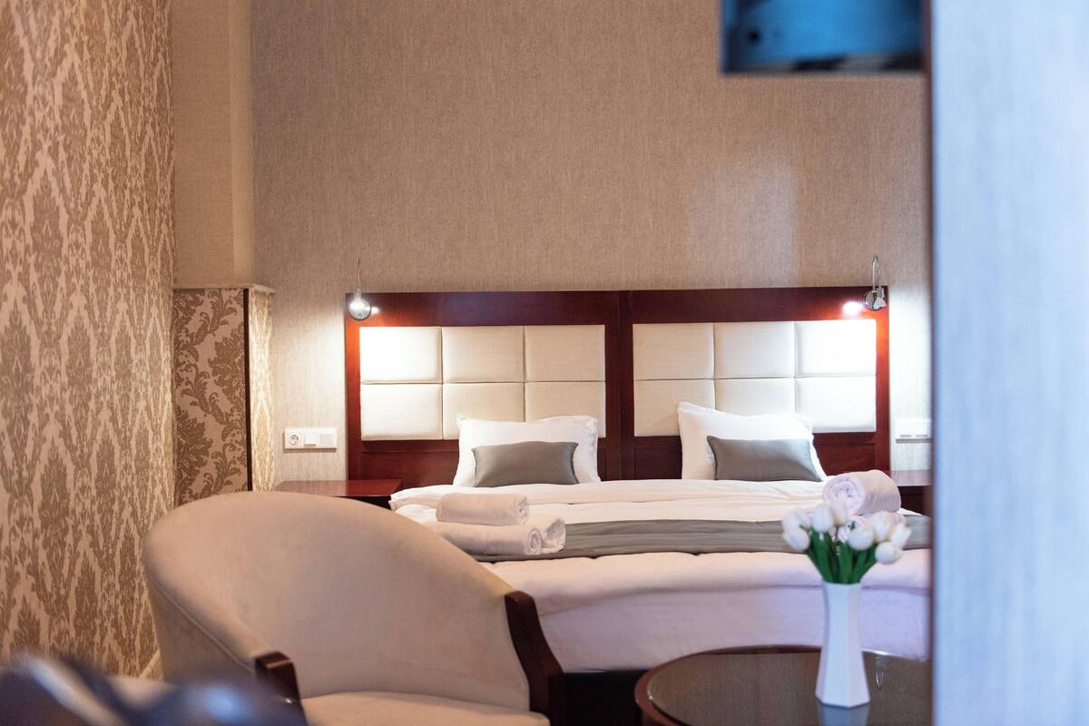 A hotel room with a large bed, a chair, and a vase with flowers.