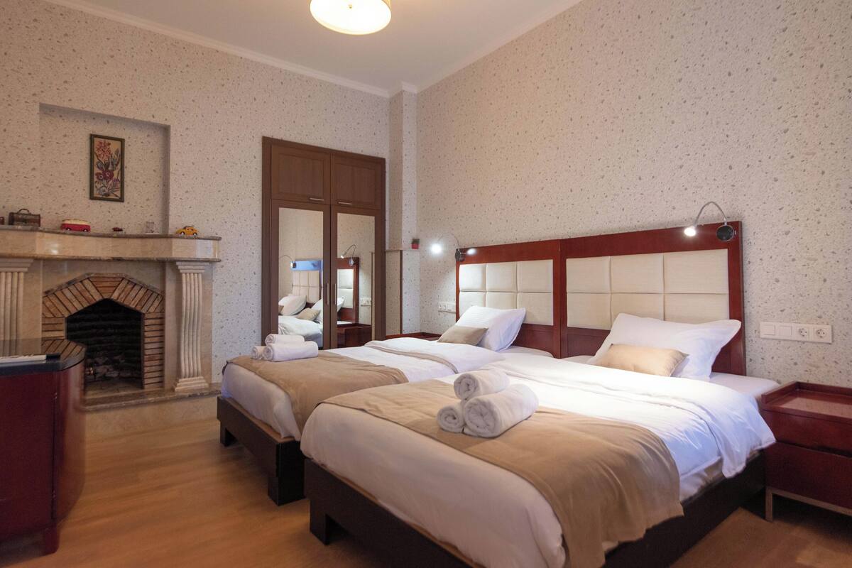 A hotel room with two beds, a fireplace, and a mirror.