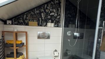 Un baño moderno con ducha, inodoro y toallero.