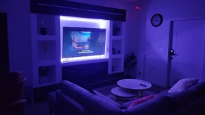 Un salon avec un téléviseur à écran plat fixé au mur, un canapé, une table basse et une porte.