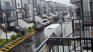 Un quartier résidentiel avec des immeubles modernes, une rue mouillée et des véhicules garés.