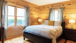 Une chambre à coucher aux murs lambrissés, avec un lit, deux lampes de chevet et une table de chevet.