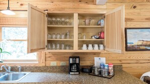 Une cuisine avec des meubles de rangement en bois, une machine à café et un plan de travail doté d’un évier.
