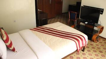Une chambre d’hôtel équipée d’un lit, d’une télévision, d’une armoire et d’un bureau.