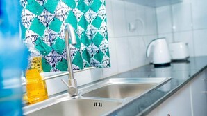 A kitchen with a stainless steel sink, a faucet, and a patterned cloth hanging above it. - Karibu Stay (Muhoza)