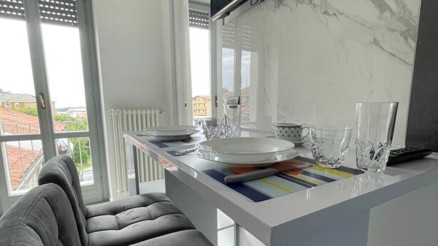 Eine moderne Küche mit weißer Arbeitsplatte, einem grauen Sofa und Blick auf die Stadt durch große Fenster.