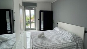 Ein modernes Schlafzimmer mit einem großen Bett, einem Kleiderschrank und einer Tür, die auf einen Balkon führt.