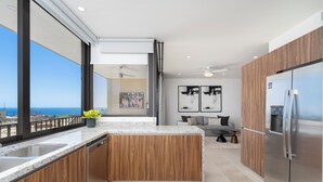 A modern kitchen with a large island, stainless steel appliances, and a view of the ocean.