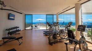 A gym with cardio machines, dumbbells, and benches.