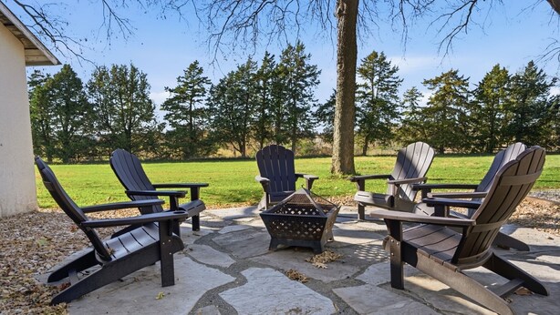 Eine Terrasse mit Adirondack-Stühlen, einem Feuerkorb und einem Steinboden.