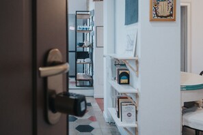 A hallway with a bookshelf, a door, and a bed.