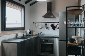 A modern kitchen with a built-in oven, a stainless steel range hood, and a window overlooking a cityscape.