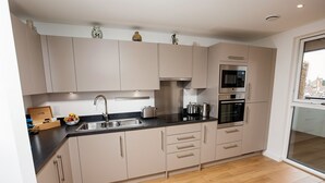 A modern kitchen with light-colored cabinets, a stainless steel sink, and a built-in oven.