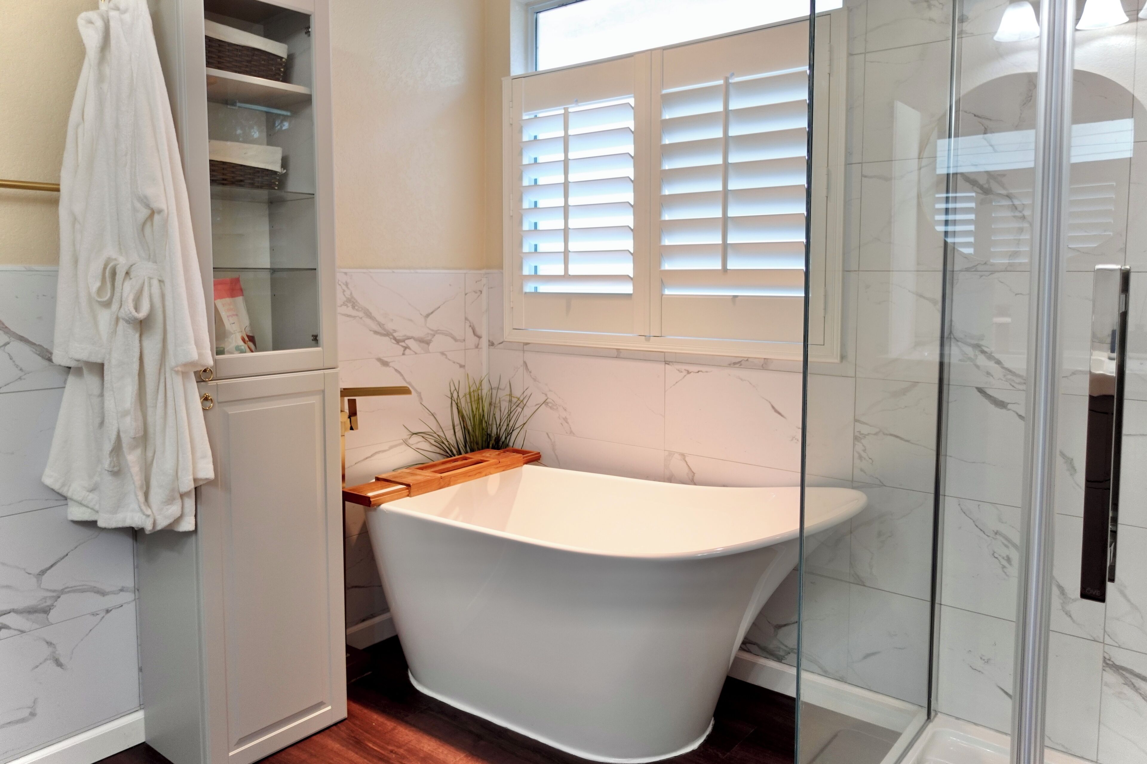Ein modernes Badezimmer mit freistehender Badewanne, einer Duschkabine aus Glas und einem Handtuchhalter.