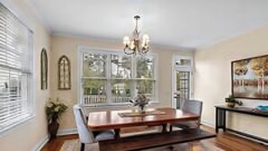 A dining room with a wooden table, chairs, a chandelier, and a large window with multiple panes. - Relaxing home w/ putting green 5 min to Pinehurst (Pinehurst)