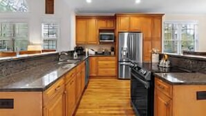 A modern kitchen with wooden cabinets, a stainless steel refrigerator, and a granite countertop. - Relaxing home w/ putting green 5 min to Pinehurst (Pinehurst)