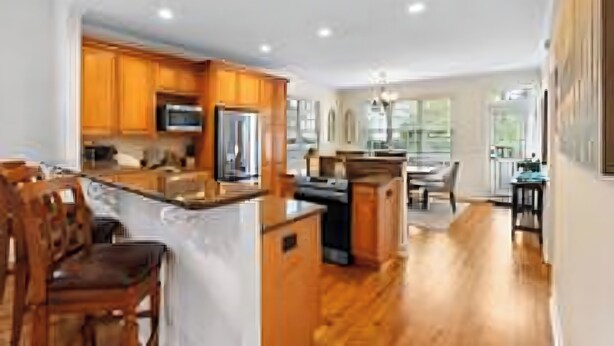 A modern kitchen with wooden cabinets, a central island, and a dining area with chairs. - Relaxing home w/ putting green 5 min to Pinehurst (Pinehurst)