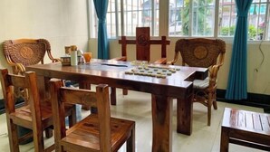 A wooden dining table with chairs, a chessboard, and a window with curtains. - Xinhe Business Hotel (Yingjiang)