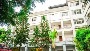 A multi-story building with a central courtyard, surrounded by trees and parked vehicles. - Xinhe Business Hotel (Yingjiang)