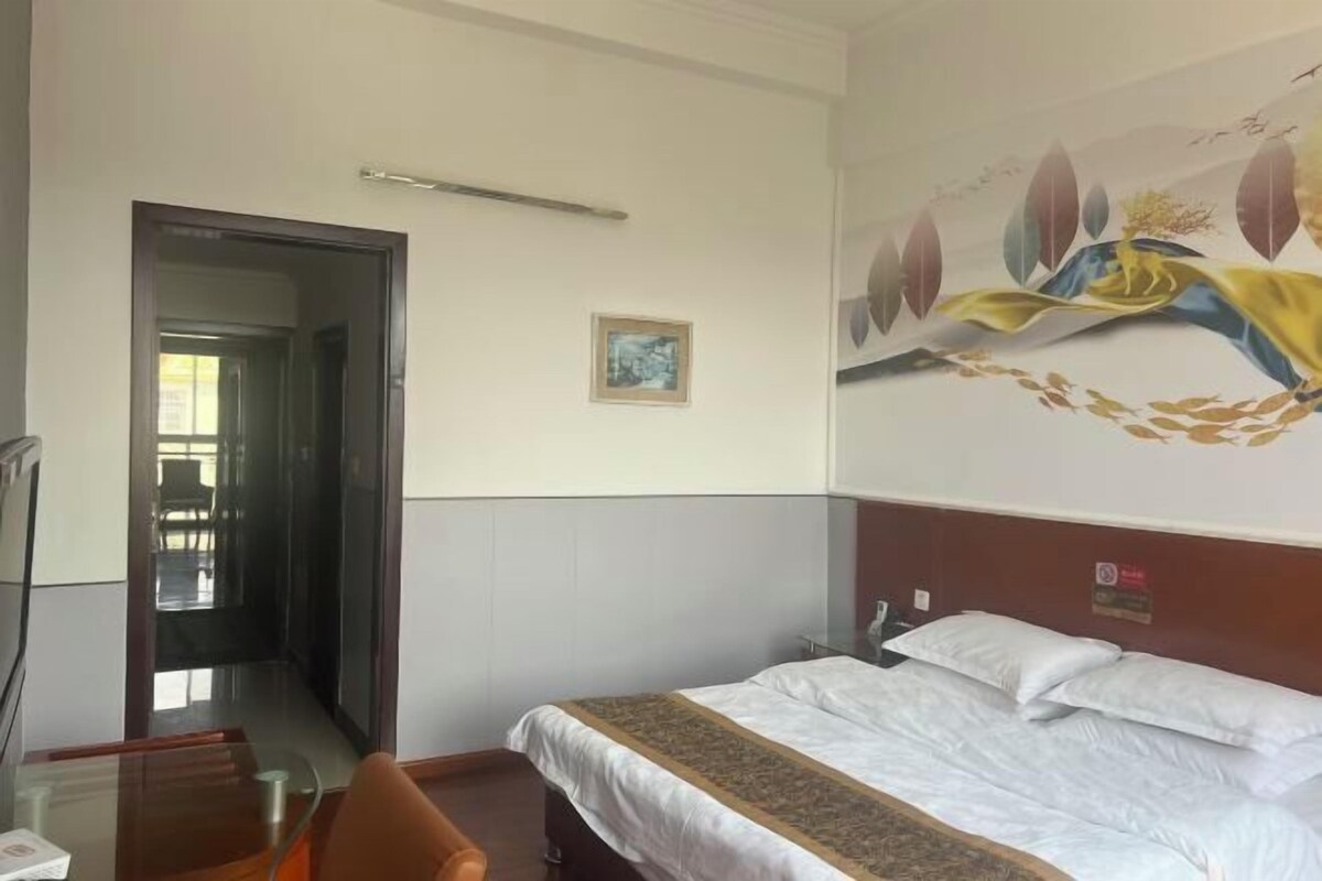 Una camera d'albergo con un letto, una scrivania, una sedia, una porta e un quadro appeso al muro.