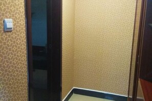 Un corridoio stretto con carta da parati decorata e una porta che conduce in un'altra stanza.