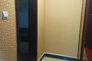 Un pasillo estrecho con papel tapiz estampado y una puerta que da a otra habitación.