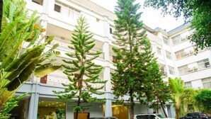 A multi-story building with a central courtyard, surrounded by lush greenery and parked cars. - Xinhe Business Hotel (Yingjiang)