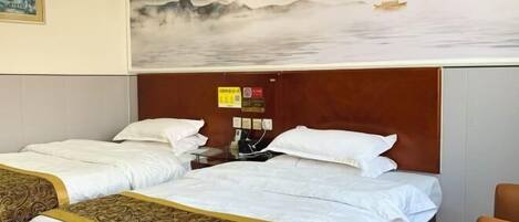 A hotel room with two beds, a wooden headboard, a painting of a landscape, and a small table with a chair.