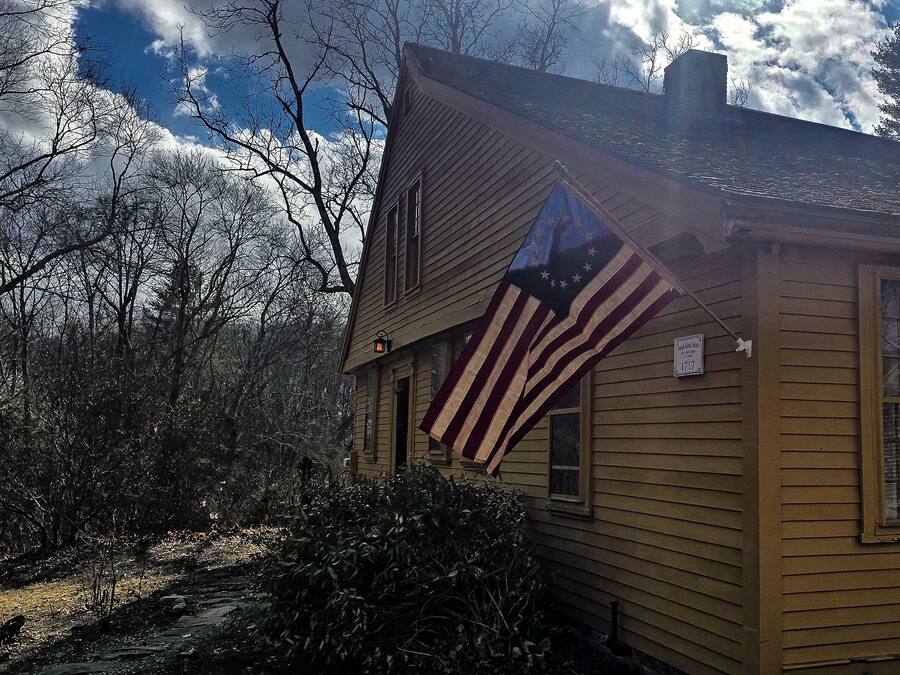 Une maison en bois jaune avec un drapeau américain sur le côté.
