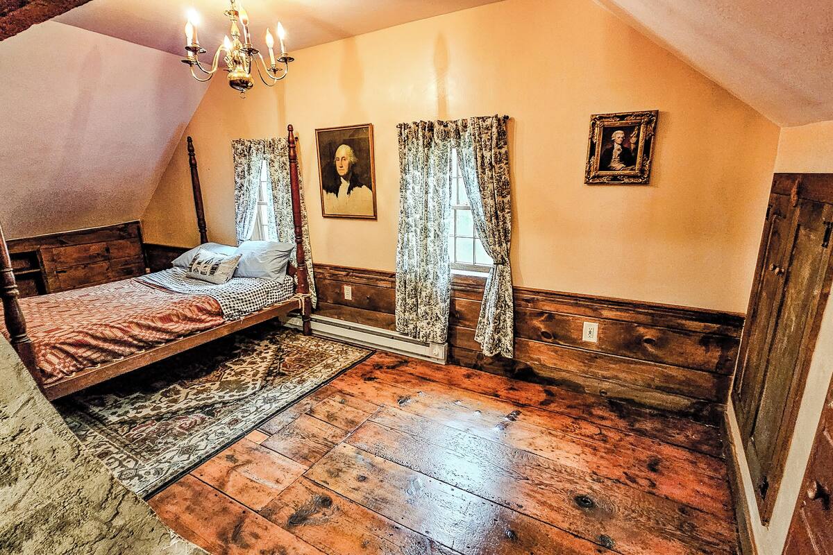Ein Schlafzimmer mit Himmelbett, Holzboden und einer Chandelier.