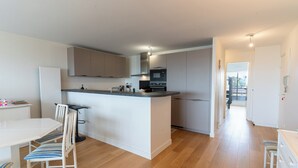 Une cuisine moderne dotée d’un îlot central, de meubles blancs et d’un coin repas avec une table et des chaises.