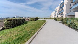 Un chemin menant à un immeuble d’appartements moderne, avec un ciel dégagé.