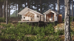 Two modern cabins in a forest, each with a deck and a small porch.