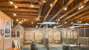 Un stand de tir intérieur avec des poutres en bois, des cibles et des postes de tir.