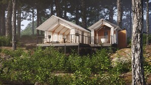 Deux chalets modernes situés dans une forêt, chacun doté d’une terrasse et d’un petit porche.