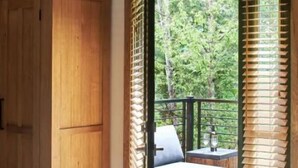 Een kamer met een houten garderobe, een bed met een gestreept laken en uitzicht op een balkon met een bank en een tafel.