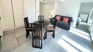 Una sala moderna con un sofá gris, sillas negras y una mesa de comedor redonda.