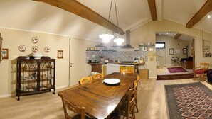 A spacious living area with a wooden dining table, a sofa, and a kitchen in the background. - Breathtaking view of the lake and castle surrounded by holm oaks and oaks (Lazio)