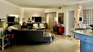 Ein modernes Wohnzimmer mit einer Couch, einem Fernseher und einem Essbereich mit einem blauen Tisch.