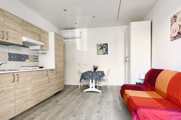 A compact living space with a kitchenette, a dining area, and a sofa.