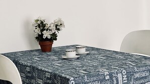 A table with a patterned tablecloth, two white cups, saucers, and a potted plant with white flowers. - M406 - Marcelli, new studio apartment facing the sea (Marcelli)