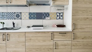 A kitchen with a white countertop, a sink, a range hood, and a backsplash with patterned tiles. - M406 - Marcelli, new studio apartment facing the sea (Marcelli)