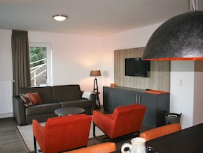 A modern living room with a sofa, two armchairs, a coffee table, and a TV mounted on the wall. - Comfortable Apartment, in a Residence 500 m. From the ski Lift (Winterberg)