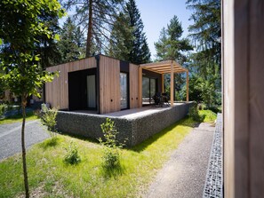 Una moderna baita con rivestimento in legno, una zona relax esterna coperta e fondamenta in pietra.