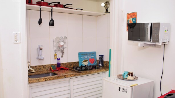 Una cocina compacta con microondas, refrigerador pequeño y pileta.