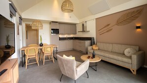 Una sala de estar moderna con sofá, sillas, una mesa de comedor y una zona de cocina.