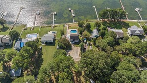 An aerial view of a residential area with houses, a swimming pool, and docks extending into a lake.