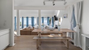 A spacious living area with a wooden dining table, a bench, and a sofa.