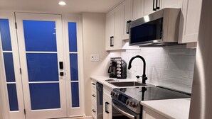 A modern kitchen with white cabinets, stainless steel appliances, and a red rug on the floor.