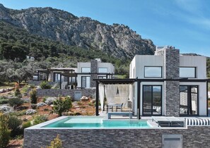 En moderne villa med pool, udendørs møbler og bjergudsigt.